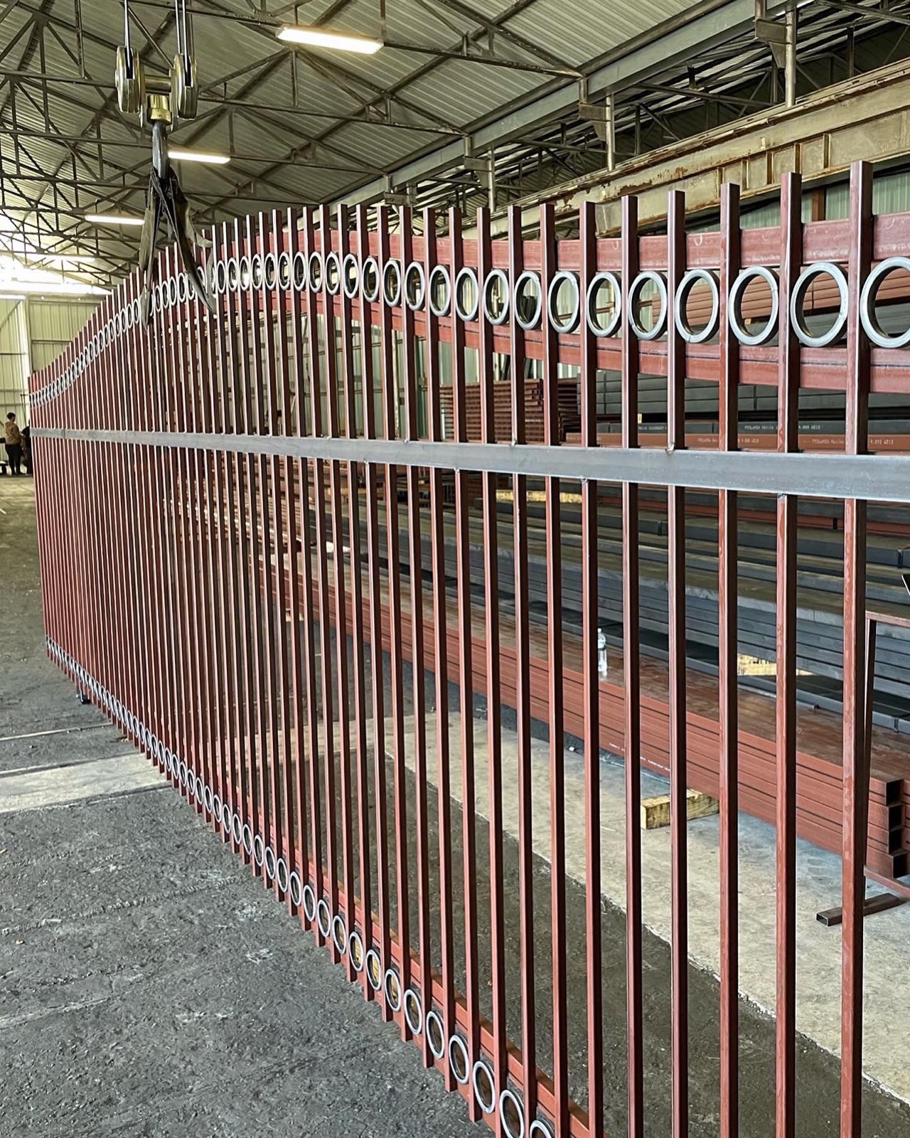 Steel driveway gate panels fabricated in the Ironrod Steel shop in Houston — primed steel pickets with ring detail, mill stock racked behind