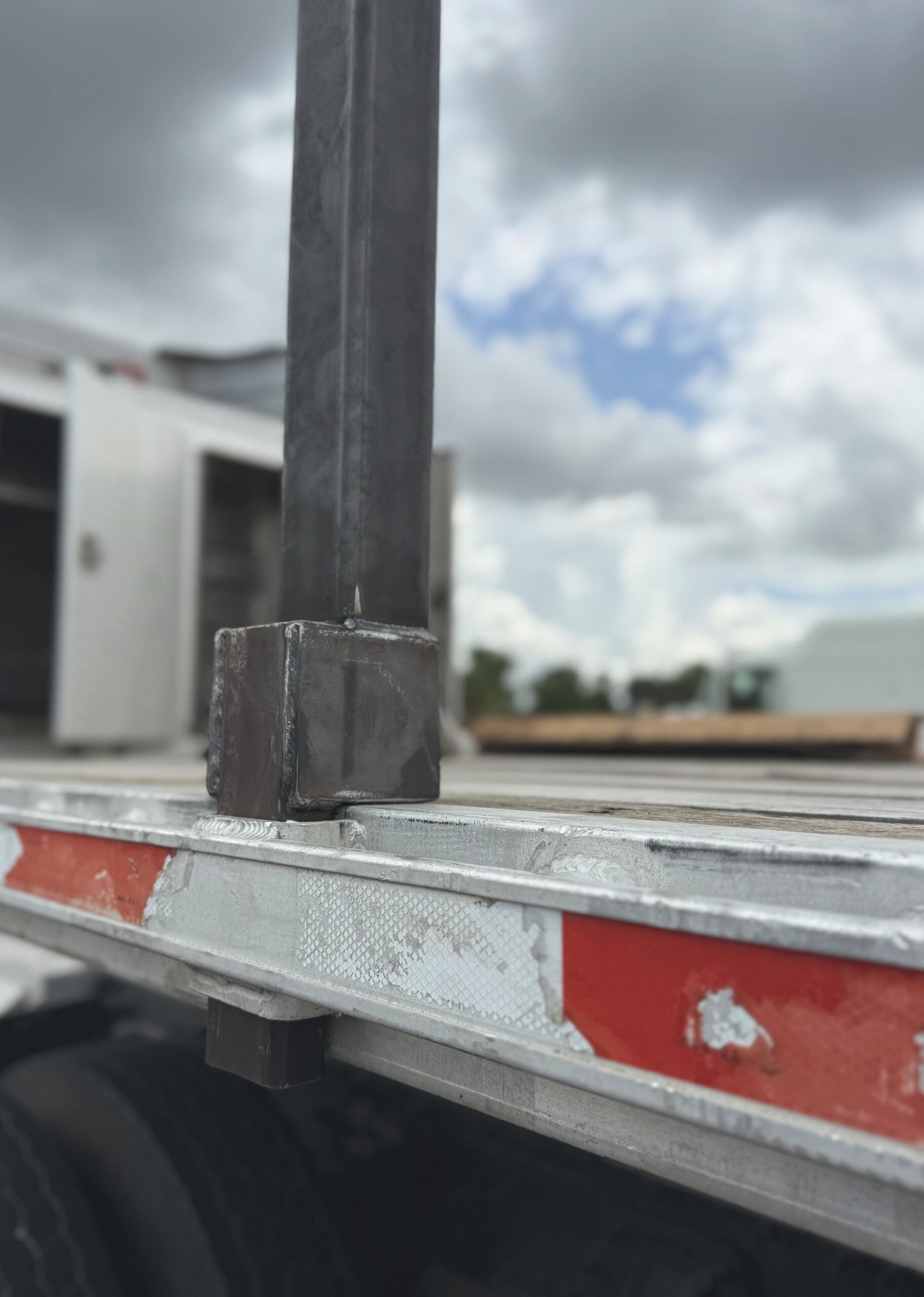 Close-up of heavy-duty pipe stake welded base dropped into a standard flatbed stake pocket on the rub rail
